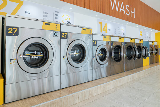 A row of qualified coin-operated washing machines in a public store. Concept of a self service commercial laundry and drying machine in a public room.