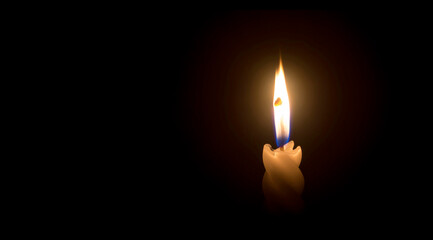 A single burning candle flame or light glowing on a spiral white candle on black or dark background...