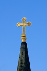 Fototapeta na wymiar Cross on a steeple against a blue sky.