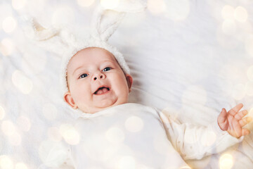 close up. smiling baby in a rabbit suit. beautiful bokeh effect from a garland