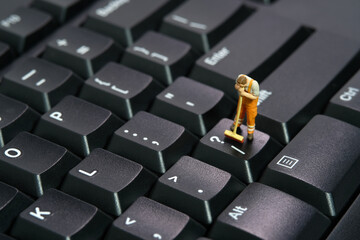 Miniature people toy figure photography. Sweeper workers cleaning mechanical keyboard using broom,...