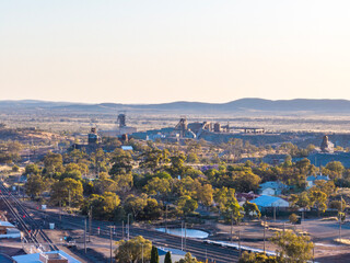 Early morning aerial zoom view of mine shafts and a beneficiation or processing plant located in Broken Hill, New South Wales, Australia. Train tracks in the foreground, mountain range in the back.