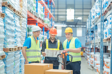 Fototapeta na wymiar Warehouse workers in helmets checking goods and supplies on shelves with goods background in warehouse worker packing in a large warehouse in a large warehouse. Logistics industry concept..