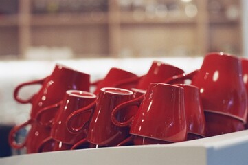 Rack of cups in a coffee shop in Red color stacked coffee mugs