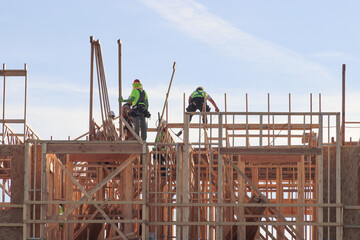 Crew of wood framing workers on top of structure of apartment building under construction