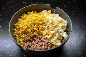 Naszykowana sałatka z tuńczykiem, jajkiem i kukurydzą w dużej szarej misce © Katarzyna