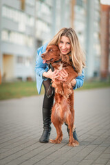 Portrait of a beautiful blonde girl with a thoroughbred English Cocker Spaniel in the city.