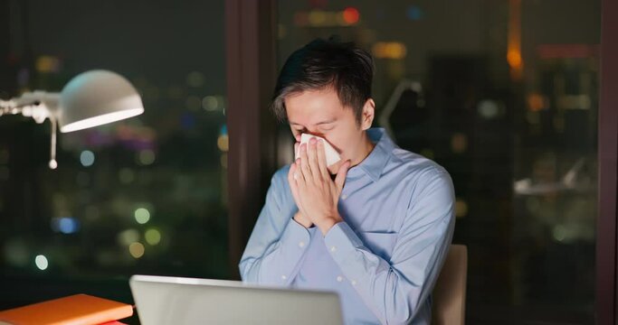 Business man sneezes at work