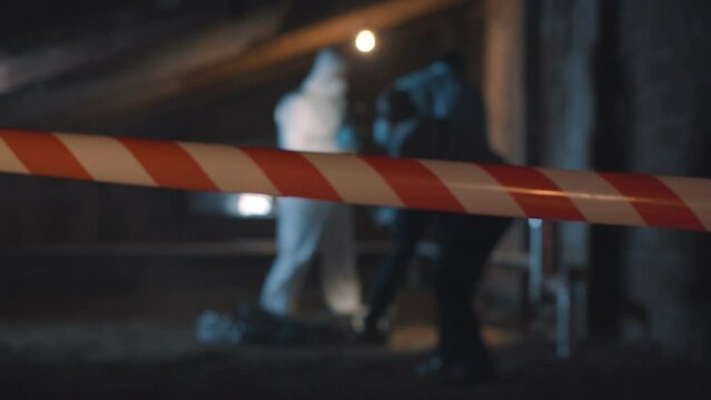Two policemen and forensic specialist taking photos of evidence and corpse on crime scene