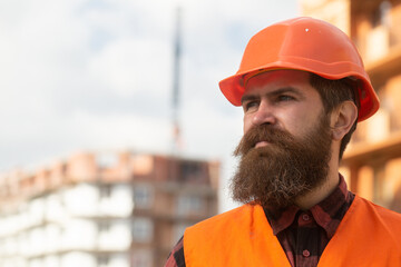 Portrait of construction builder. Man builder worker in helmet posing on construction site.
