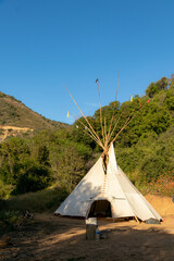 teepee en bosque de arboles con un cielo azul en la montaña 