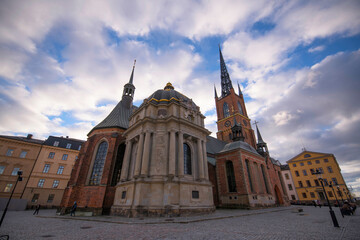 Obraz premium Old brick church with towers and apses a winter day with dark clouds and low sun in Stockholm