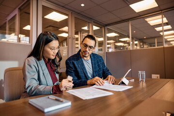 Multiracial colleagues going through business reports during meeting in office.