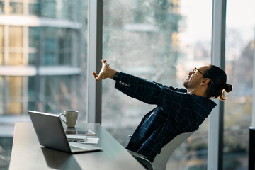Overworked businessman stretching after working on computer in office.