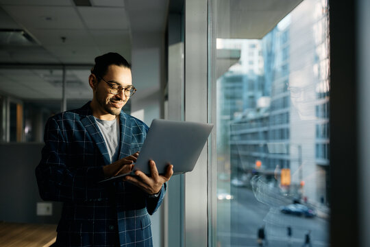 Happy Hispanic businesswoman working on laptop in office.