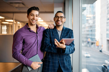 Young happy male colleagues in office looking at camera.