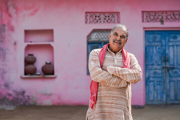 Old and senior indian farmer standing and giving happy expression