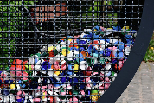 Recycled plastic bottle caps in metal cage container. reduce reuse recycle concept. RRR abbreviation. colorful close-up view. environment and ecological footprint theme. selective focus.