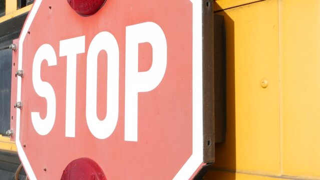 Red stop sign, yellow school bus in California, USA. Traffic warning on passenger schoolbus or shuttle in America. Public transportation safety on road. Caution or attention signage. Education concept