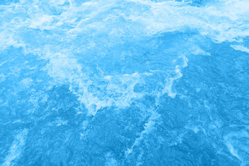 Bluewater waves on the surface ripples blurred. Defocus blurred transparent blue colored clear calm water surface texture with splash and bubbles. Water waves with shining pattern texture background.