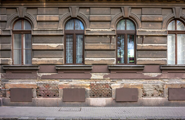 Frontal view of a beige brown brick facade in the old town of Budapest with a sidewalk in the...