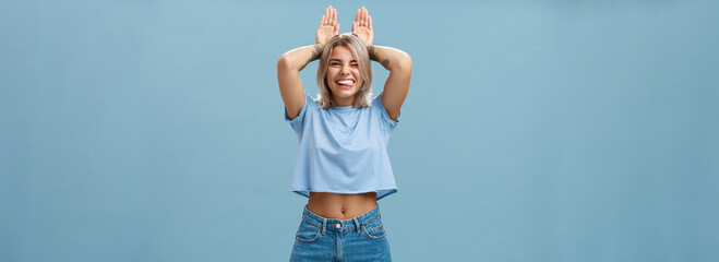 Time to relax. Portrait of happy playful cute blonde girl in trendy t-shirt with pierced belly and...