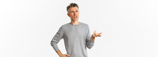 Image of confused middle-aged man cant understand something, raising hand and looking puzzled left, standing clueless over white background - obrazy, fototapety, plakaty