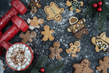 Obraz na płótnie Canvas Gingerbread cookies, dumbbells, hot chocolate or cocoa with marshmallows, Christmas tree branches. Fitness holiday season, winter diet composition. Gym workout, dieting flat lay concept.