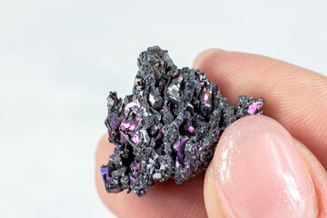 Woman hand holding shiny black Carborundum crystal (Moissanite or Silicon Carbide) on light...