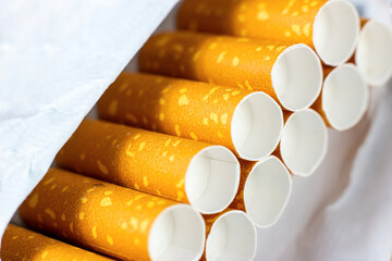 Many orange cigarette filters in the opened pack close up. Smoking addiction and nicotine dependence concept.