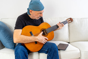 Old Man Practicing to Play Guitar Sitting on Sofa at Home