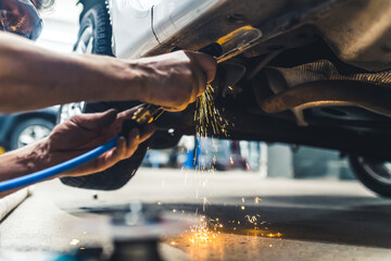 Blue-collar worker concept. Angle grinder in use. Dangerous heat sparkles. Two hands of caucasian mechanic. Indoor low angle view. High quality photo