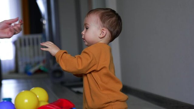 Small kid wearing orange sport suit giving a white thing to his mom. Mother gives the issue to her son again and he takes it willingly.