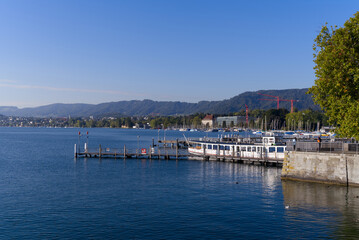 Fototapeta premium Scenic view over Lake Zürich seen from City of Zürich with pier and Swiss Alps in the background on a sunny late summer day. Photo taken September 22, 2022, Zurich, Switzerland.