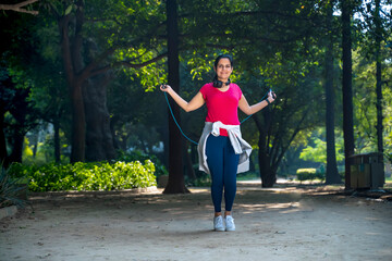 young Indian woman with jump rope and doing skipping workout in a park.