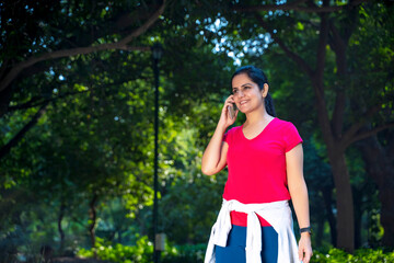 Young indian woman doing jogging and talking on mobile.