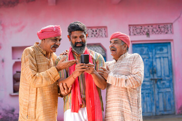 Three Indian villagers watching some detail in smartphone.