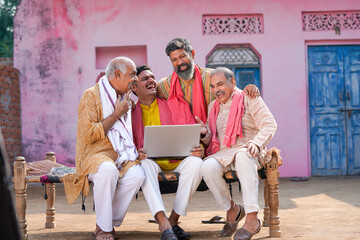 Indian villagers setting at in front of home and using laptop.