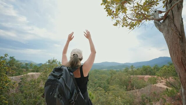Back view of woman hiker and backpack with arms raised on top of mountain and looking at the mountain view. Enjoy nature adventure vacation travel