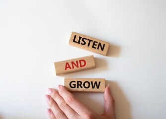 Listen and grow symbol. Concept words Listen and grow on wooden blocks. Beautiful white background. Businessman hand. Businessman hand. Business and Listen and grow concept. Copy space.