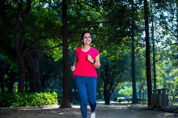 young indian woman with earphones listening music during jogging at park.