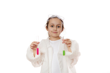 Lovely child girl, future chemist scientist in lab coat, smiles looking at camera, holding out test tubes with liquid chemical, isolated on white background. Kids learning chemistry. Education concept