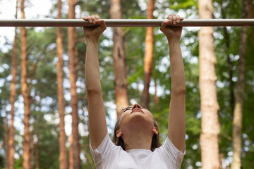 teenager girl pulls up on the horizontal bar in a street gym