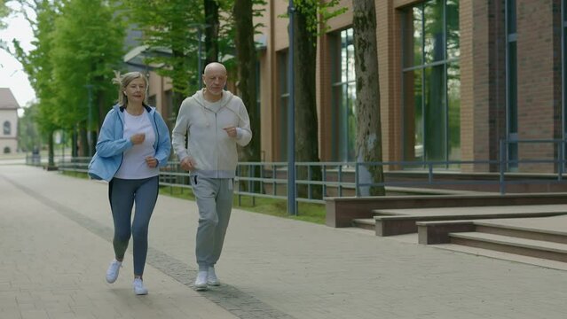 Active senior husband and wife having fun doing cardio exercise and running together outdoors. Sport and healthy lifestyle concept. Aging Youthfully