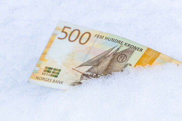 Norwegian 500 kroner banknote lying in the snow, Financial concept, spending freeze