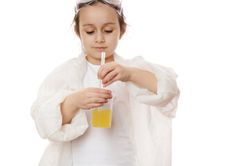 Selective focus on hands of a smart child girl, young chemist scientist wearing lab coat, mixing yellow liquid chemical solution in beaker, with laboratory stick, on white background. Chemistry lesson