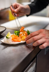 chef cooking slice salmon fish and shrimp with salad on kitchen