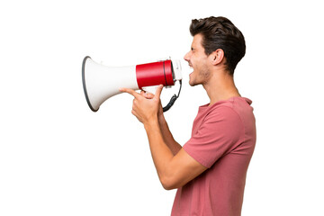 Naklejka premium Young handsome caucasian man over isolated background shouting through a megaphone