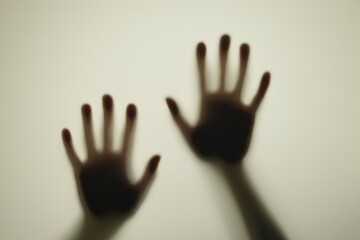 Blurred shadows of hands behind frosted glass, concept of nightmares, horror, domestic violence
