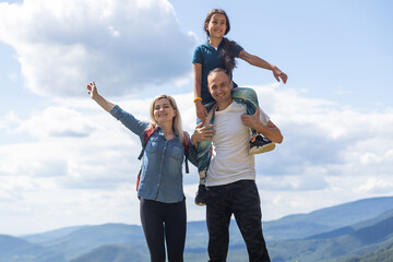 Family hiking parents with child outdoor travel in mountains active vacations lifestyle mother and father backpacking together.